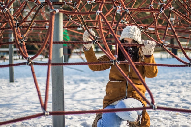 Foto ritratto di una donna accovacciata sotto le corde in un parco coperto di neve