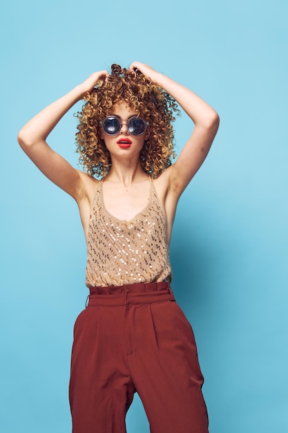 Portrait of a woman Curly hair sunglasses fashionable clothes hands over head lipstick