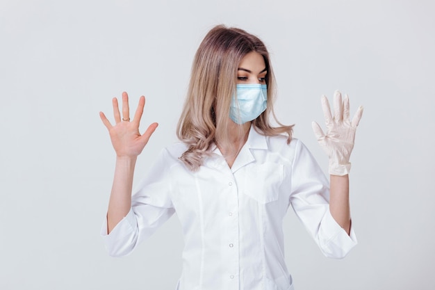 Portrait of woman doctor with face mask doctor shows hands one gloved hand and the other without