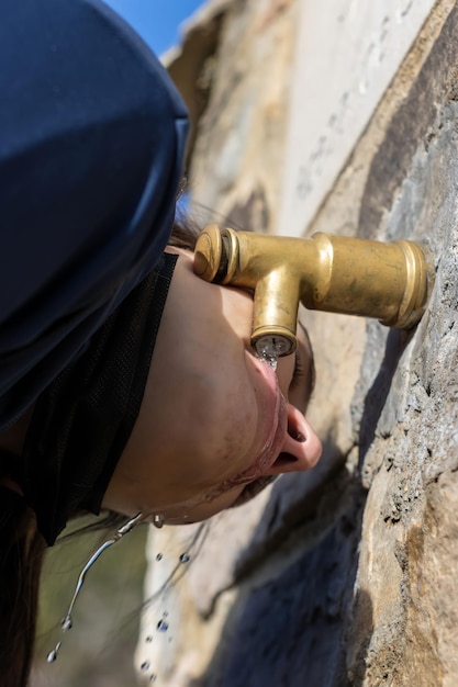 Portrait of a woman drinking water at a fountain