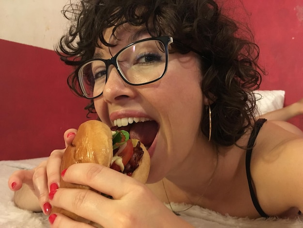 Photo portrait of woman eating burger at home