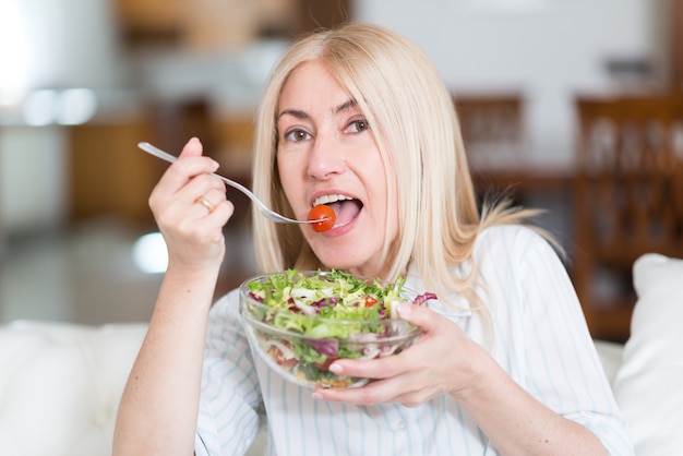 Portrait of a woman eating a salad in her apartment