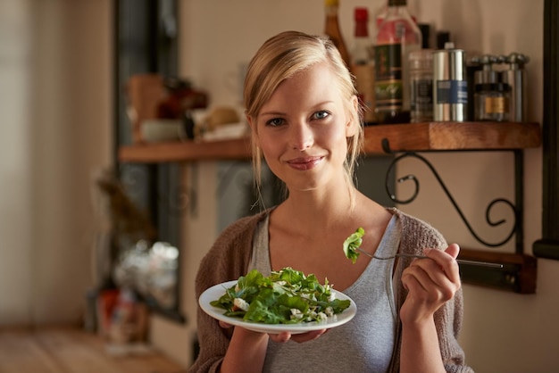 Photo portrait woman and eating salad in kitchen at home nutrition and fresh leafy greens for healthy diet vegetables bowl and face of hungry person with food fork and organic vegan meal for wellness