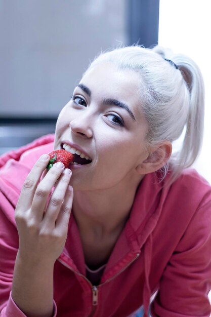 Photo portrait of woman eating strawberry