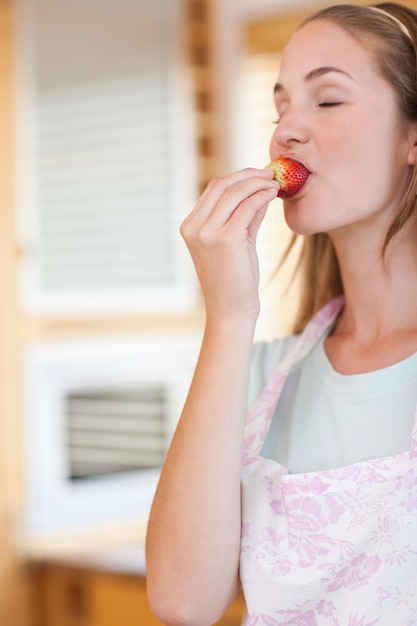 Portrait of a woman eating a strawberry