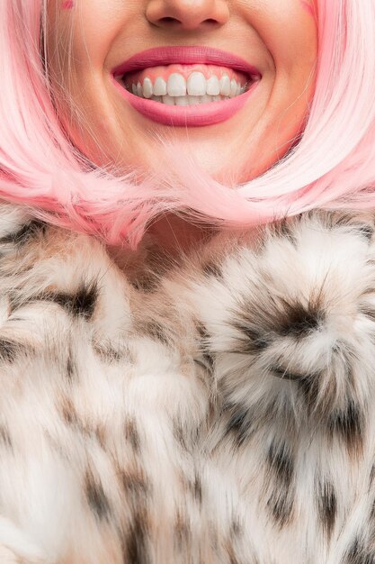 Photo portrait of woman in eco fur coat and pink hair wig close up