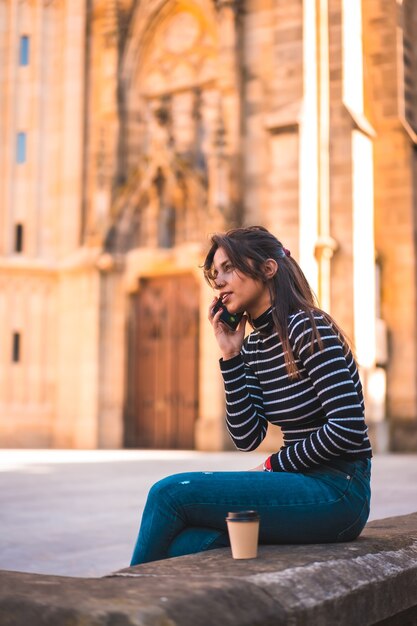 Ritratto di donna che gode del caffè nel parco mentre si utilizza il cellulare