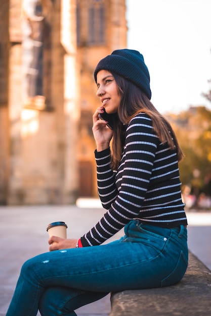 portrait woman enjoying coffee in park while using mobile