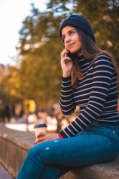 portrait woman enjoying coffee in park while using mobile