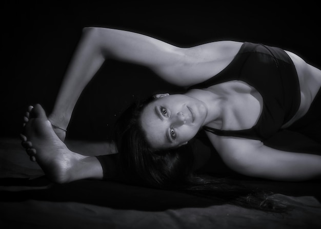 Foto ritratto di una donna che si esercita sul pavimento in camera oscura.