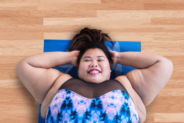 Photo portrait of woman exercising while lying on hardwood floor