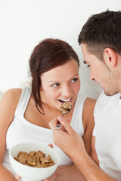 Portrait of a woman fed with cereal by her man