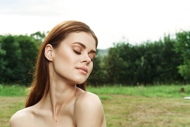 Portrait of a woman in a field outdoors bare shoulders clear skin closeup