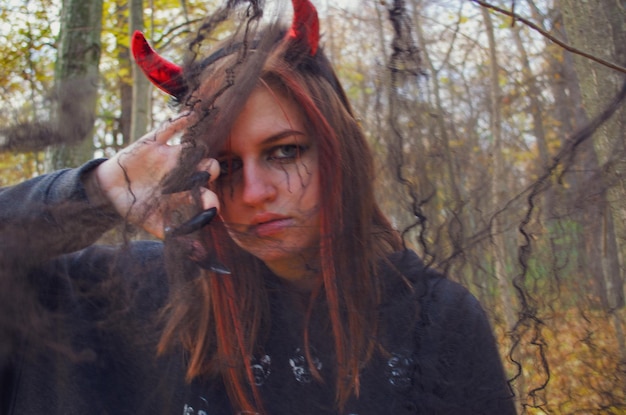 Foto ritratto di una donna in una foresta halloween con le corna rosse