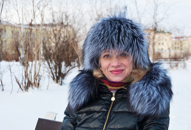 Portrait of a woman in a fur hat. Winter in the city park.