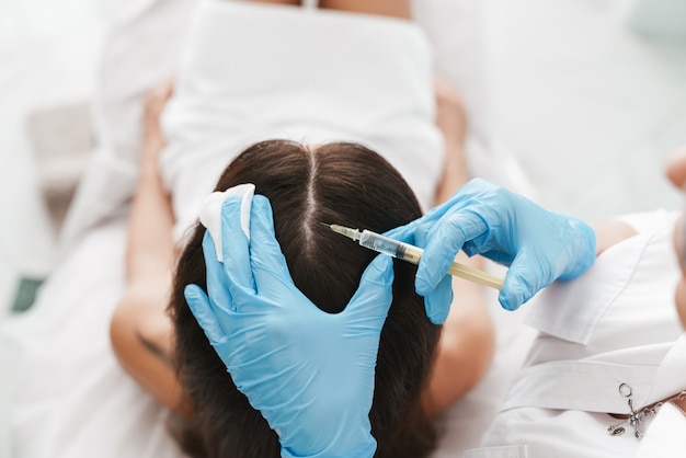 Portrait of woman getting mesotherapy treatment in head for stimulation of growing hair by specialist in beauty salon