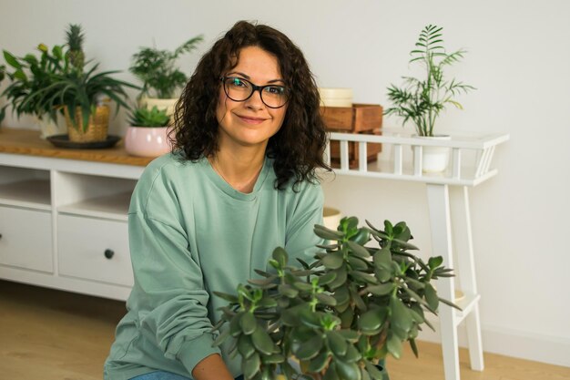 Foto la donna del ritratto coltiva le piante in vaso a casa innaffiando e si prende cura dei fiori giardinaggio e concetto di cura delle piante d'appartamento