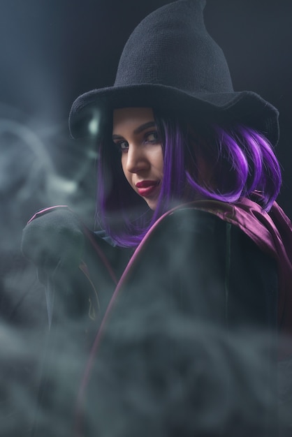 Portrait of woman in halloween costume with bright make up and purple hair