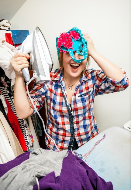 Portrait of woman having fun with iron during housework