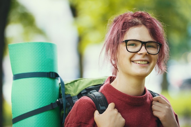 Photo portrait of woman hiker in casual clothes with backpack in the park close up