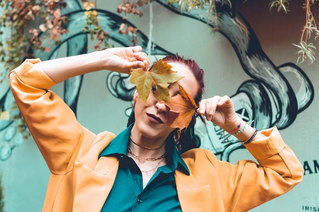 Portrait woman holding autumn leaves with her hands over her face