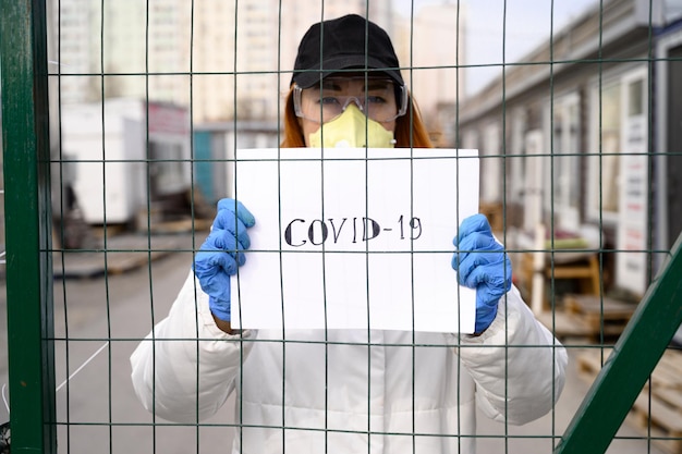 Foto ritratto di una donna con uno striscione visto attraverso la recinzione