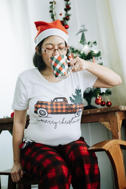 Photo portrait of woman holding christmas tree at home