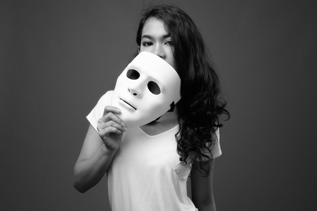 Portrait of woman holding face against gray background