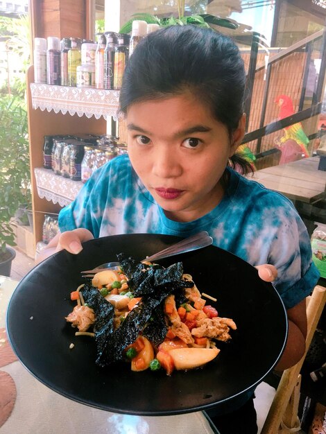 Foto ritratto di una donna che tiene il cibo in un piatto in un ristorante