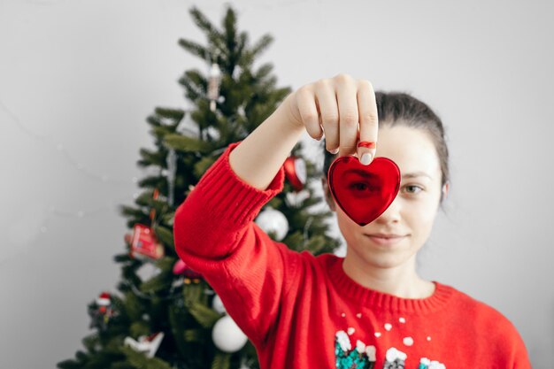 Foto ritratto di una donna in forma di cuore vicino all'albero di natale a casa