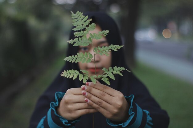 Foto ritratto di una donna con le foglie sul viso