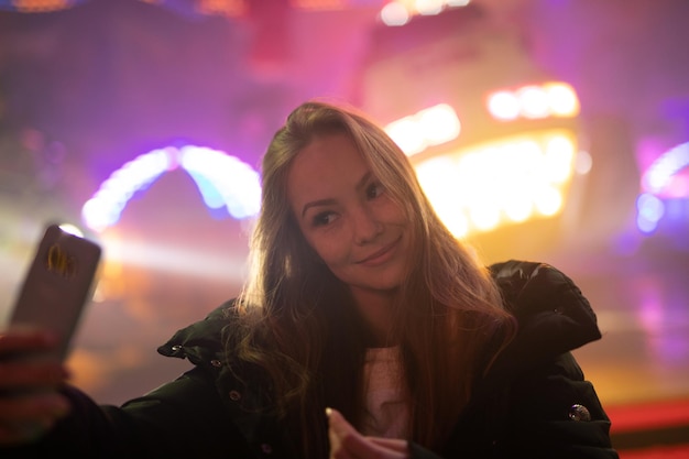 Photo portrait of woman holding mobile phone at night