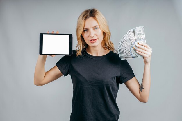 Portrait of a woman holding money and showing blank tablet computer screen