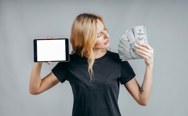 Portrait of a woman holding money and showing blank tablet computer screen