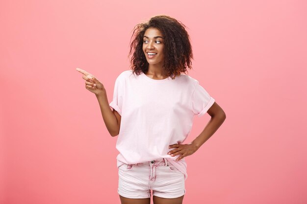 Portrait of woman holding pink umbrella against gray background