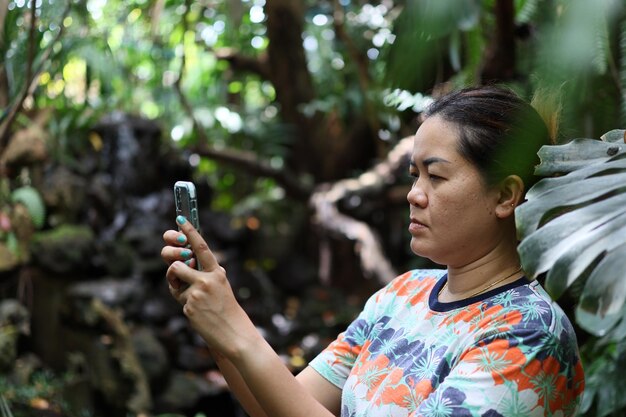 Foto ritratto di una donna che tiene una pianta nella foresta