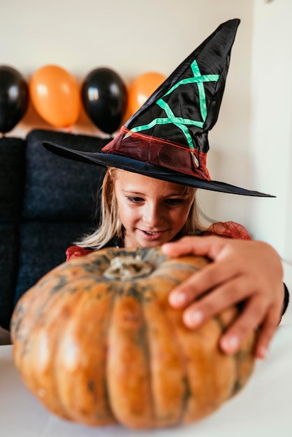 Portrait of woman holding pumpkin against wooden wall during halloween