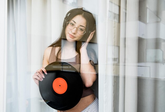 Portrait of woman holding record seen through window