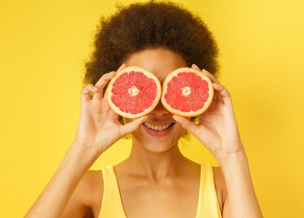 Portrait of woman holding strawberry against gray background