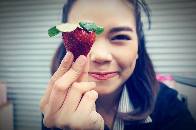 Foto ritratto di una donna con una fragola in mano