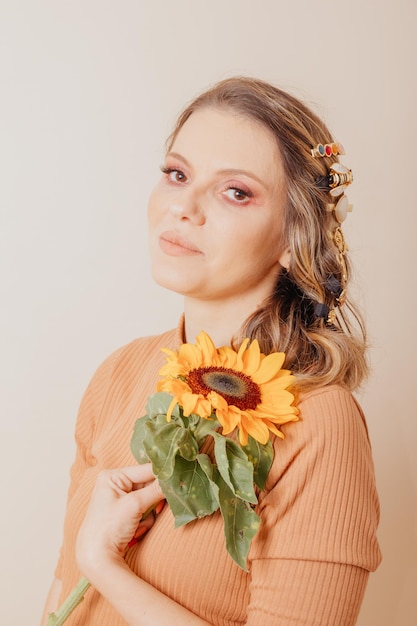 Ritratto di donna in possesso di un girasole donna con accessori per capelli clipon su sfondo crema