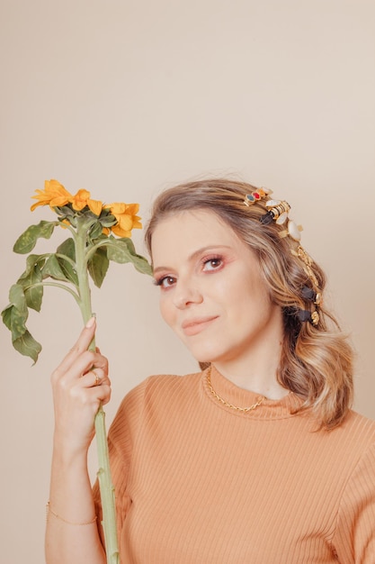 Portrait of woman holding a sunflower Woman with clipon hair accessories on cream background