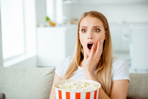 Donna del ritratto a casa che mangia popcorn