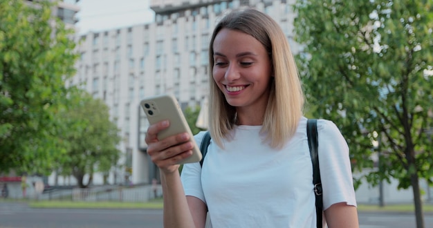 Portrait of woman is using smartphone after ride on electric kick scooter in the street Renewable energy transport