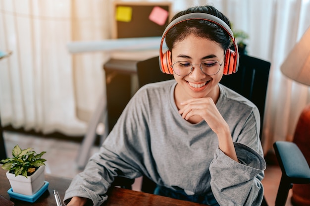 Portrait woman is working in the living room at home wearing headphones listening to music