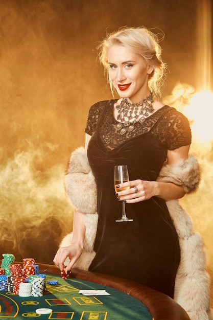 Portrait of woman keeping poker chips near table in casino