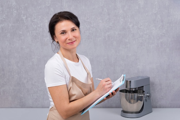 Портрет женщины в кухонном фартуке с документами в руках. Кук выписывает рецепт.
