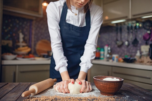 Portrait of a woman kneading dough in the kitchen