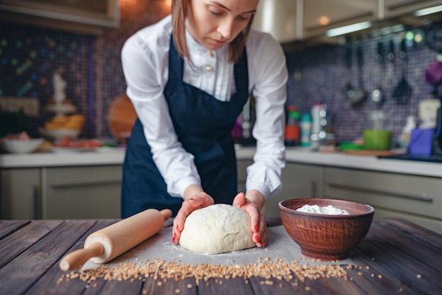 Portrait of a woman kneading dough in the kitchen