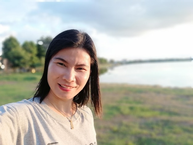 Photo portrait of woman at lakeshore against sky